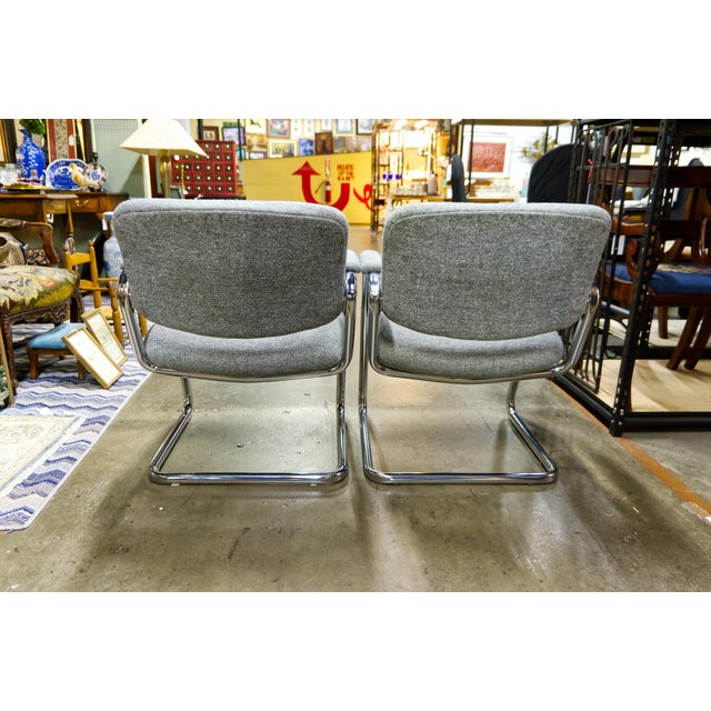 A pair of modern style cantilever chromed steel frame armchairs with gray tufted upholstery. Unmarked.