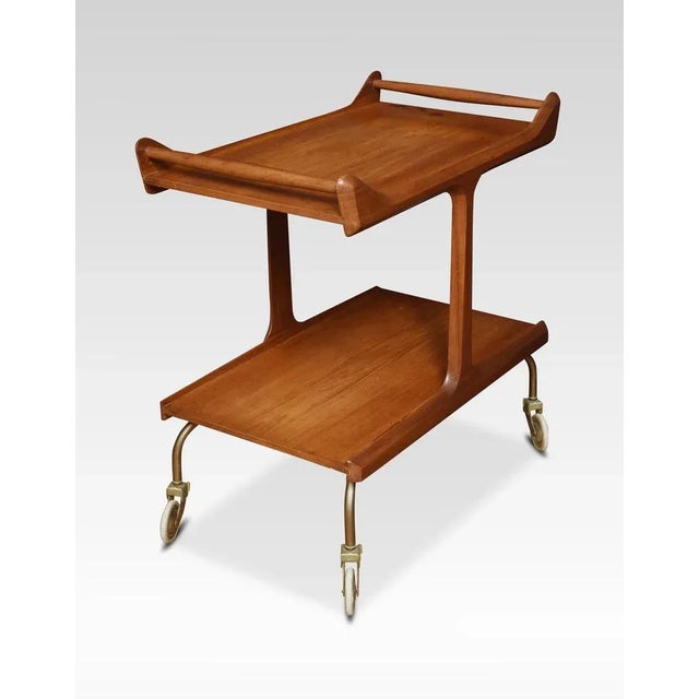 Walnut trolley, with shaped handles above the large shelf, supported on platform ends and similar under tier. All raised...