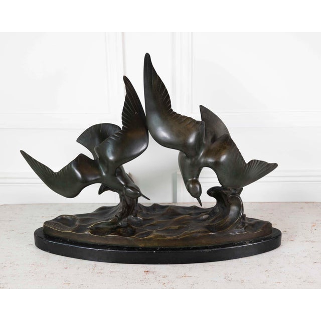 A bronze sculpture signed J.B. Leonard, this twentieth-century French work depicts two seagulls in flight above a wave-...