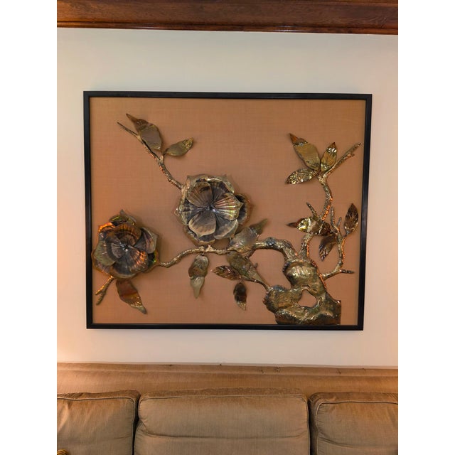This beautiful large brass floral sculpture is framed in black with a beige cloth background, and hangs from a standard...