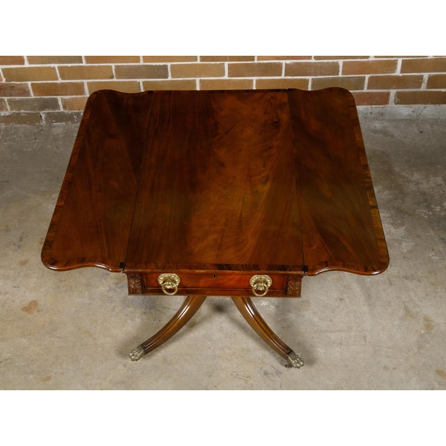 An English Regency period mahogany Pembroke table from the 19th century with drop leaves, cross-banding, single drawer and...