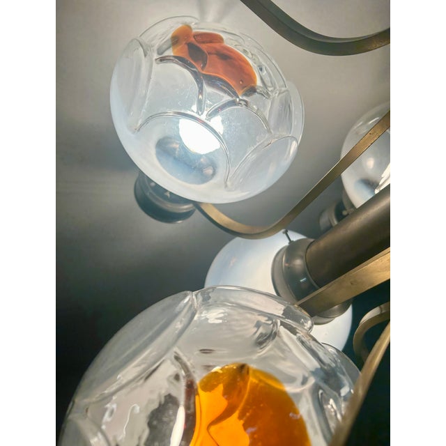 The metal and brass chandelier in typical 70s style has glass blown by master glassmakers similar to Mazzega in...