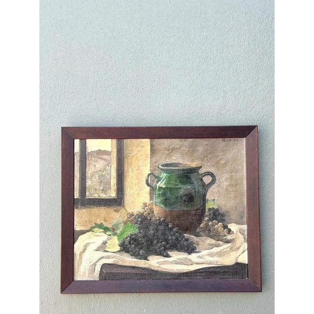 This vintage oil painting is a quiet, sunlit still life in the European tradition, with a glazed green jug anchoring a...