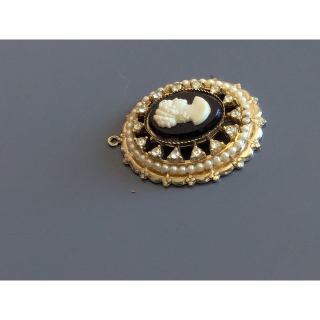 Signed CORO cameo pendant black background and white cameo with rhinestones placed in settings and faux pearls.