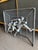 This vintage metal wall sculpture depicts three athletic figures in high relief against a wire mesh soccer goal frame....