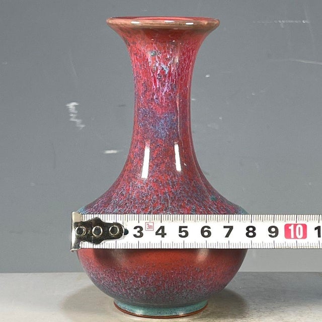 A striking small Chinese porcelain vase featuring a classic Jun ware style flambe glaze. The vase has a pear shape with a...