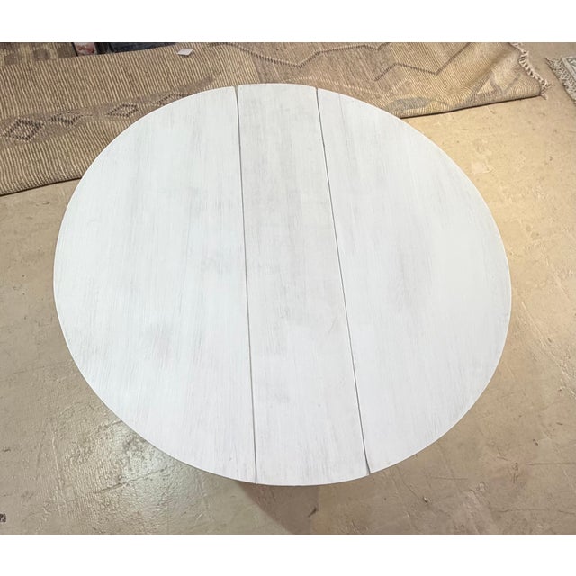 Vintage drop-leaf accent table featuring a softly whitewashed finish that highlights the natural wood grain. The round...