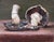 This oil painting depicts two portabella mushrooms, their rich, earthy tones contrasting with a muted background. The...