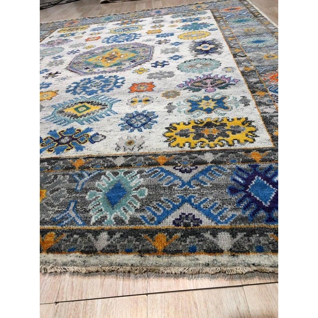 This hand knotted pile rug features a Kazak style design and is woven from pure wool. The primary color palette consists...