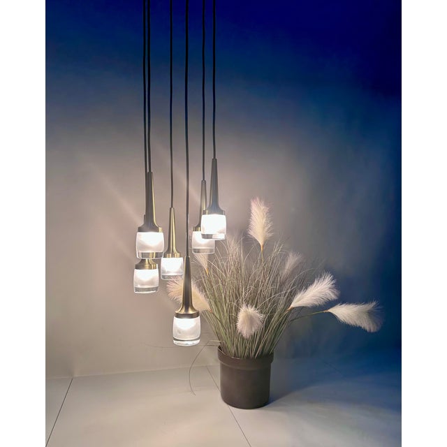 An impressive cascade hanging lamp of sculptural modern elegance in heavy matted glass and brass-plated metal. Produced in...