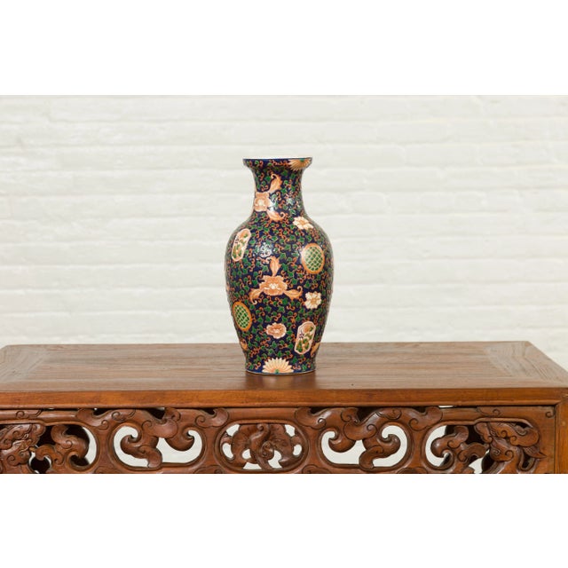 A Chinese contemporary hand painted vase with cobalt blue ground, green and orange floral decor. Charming us with its...