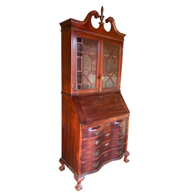 Antique-style mahogany secretary bookcase with a glazed upper cabinet, slant-front writing desk, and four serpentine...
