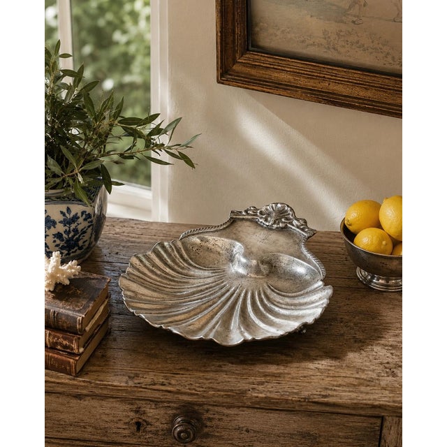 A striking late-19th-century English serving dish fashioned as a deeply fluted scallop shell. The silver-plated surface...