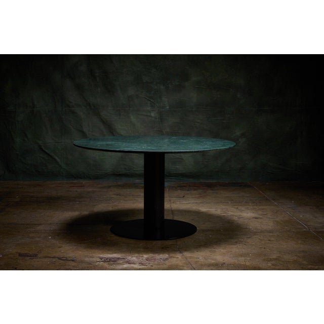 Gubi round table featuring a green marble top and a black metal pedestal base, ideal for dining or accent use. - The...