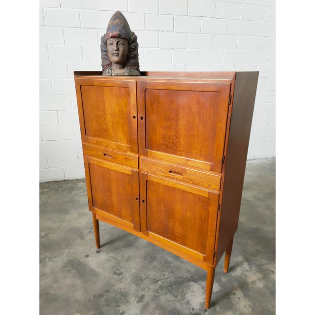 : Tall sideboard made of solid teak wood, featuring four doors with various shelves, and two separate drawers, one of...