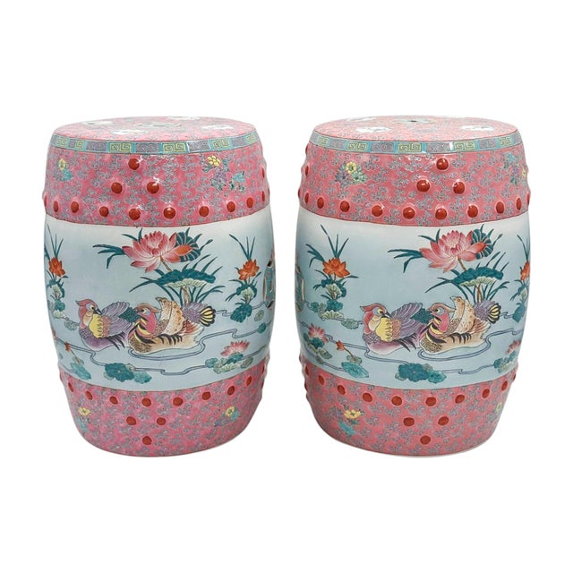 A vibrant pair of famille rose porcelain garden stools, decorated with traditional figural and botanical scenes in a soft...