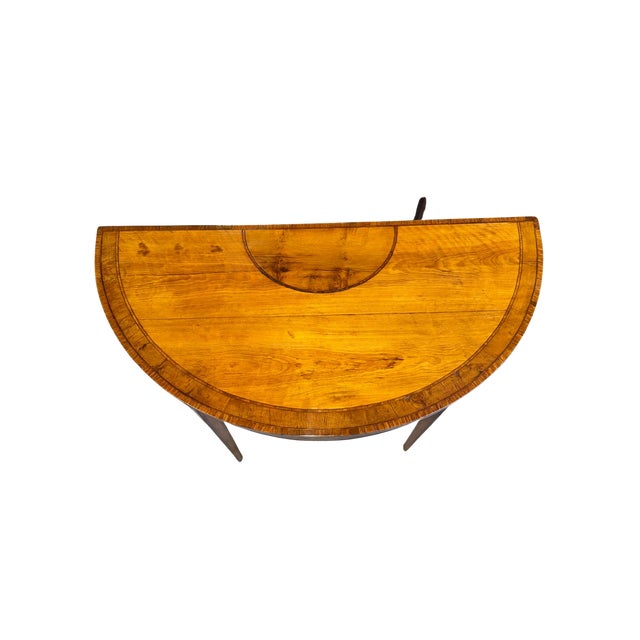 Elegant English George III demilune console table in finely figured satinwood, featuring a crossbanded top with delicate...