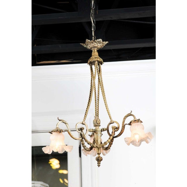 A French Louis XVI style three-light bronze chandelier from the 19th century, with flaming torch, scrolling arms, garlands...