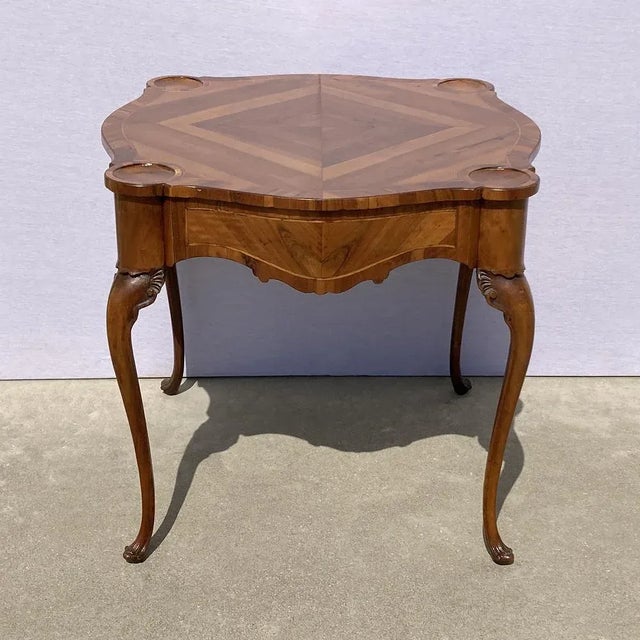 Elegant 18th-century game table in walnut and walnut burl, of wavy line and very slender proportions with a lively edge...