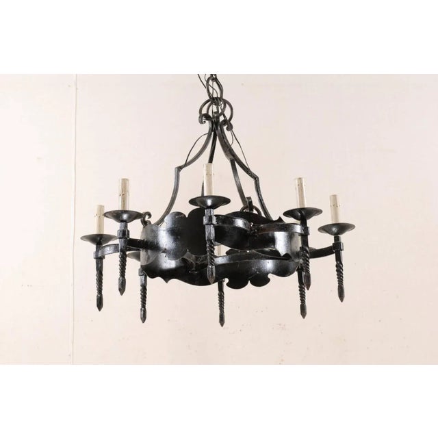 A French circular iron eight-light chandelier from the mid-20th century. This vintage French hand-forged iron chandelier...