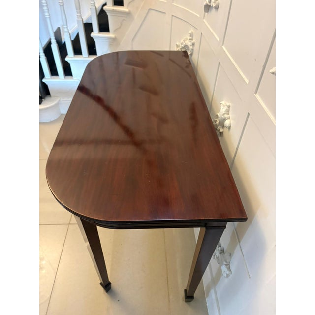 A very elegant antique mahogany demi lune console table of classic Georgian form, having a beautifully figured top with a...