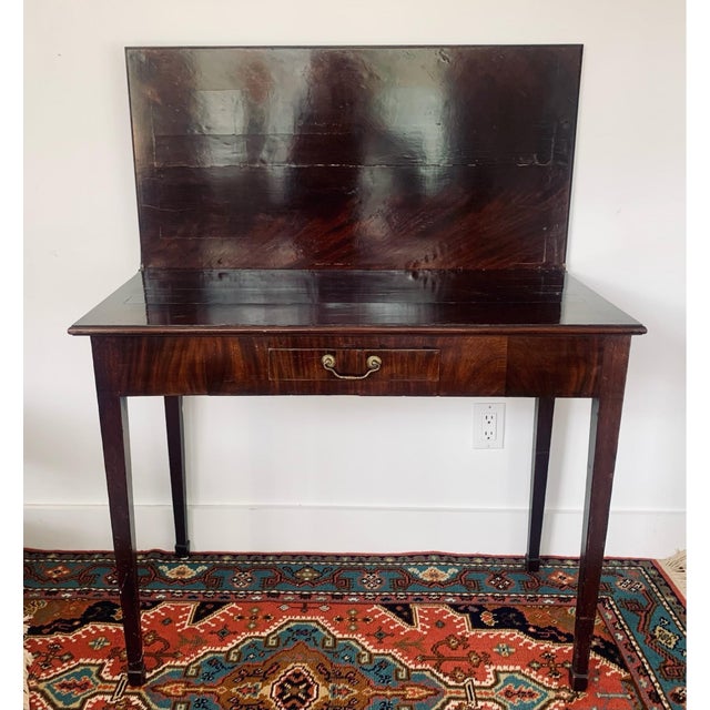 An antique Georgian period and elegantly proportioned mahogany flip-top card or game table with flame grain veneers,...