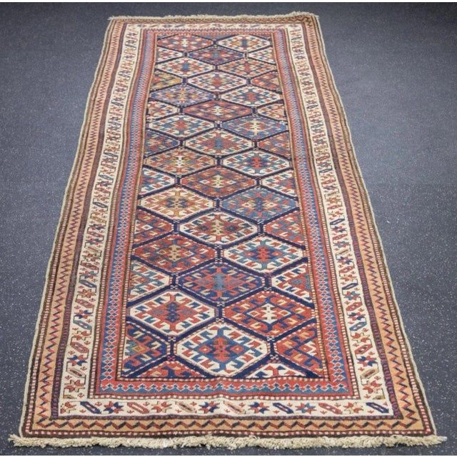 Light wool warps mark it as a west Caspian village Kuba long rug (kellegi). Dark blue field is closely covered by hexagons...