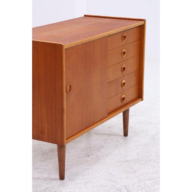 Vintage teak chest of drawers with five spacious drawers and a side cabinet. The round wooden handles, the neatly framed...