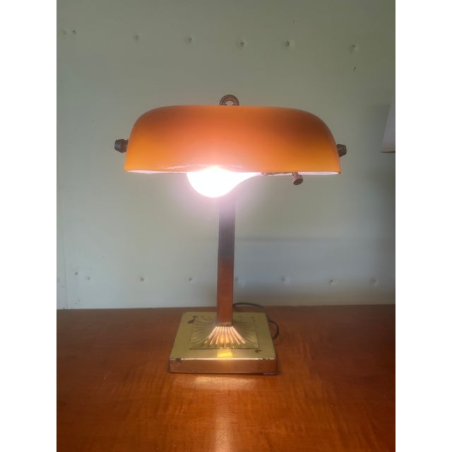Sophisticated and elegant vintage bankers style lamp with beautiful orange glass shade. This lamp is made out of brass and...
