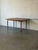 This minimalist dining table features a clean rectangular silhouette with gracefully tapered legs. The fixed top...