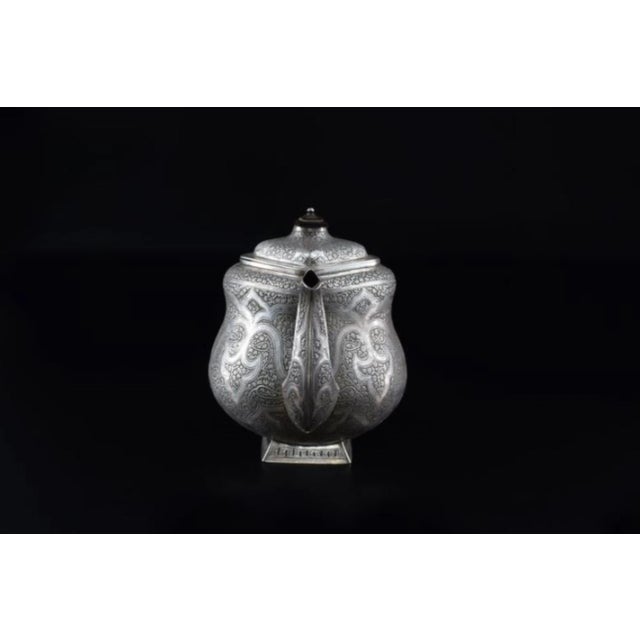 Large sterling silver teapot from the 1950s with rich Moorish-style engraving and a sculpted wooden handle. At...