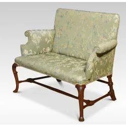 Walnut framed love seat, the solid walnut frame with a floral green upholstered back, seat and scrolling arms, raised on...