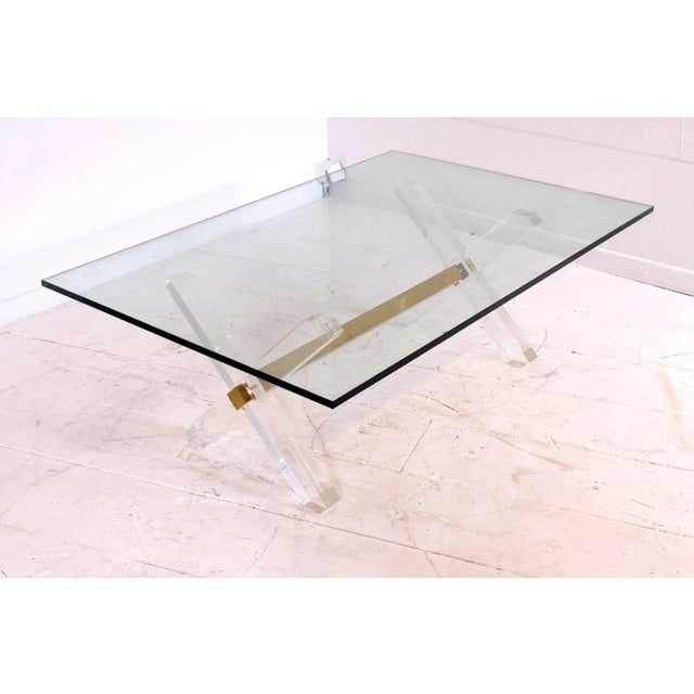This vintage coffee table, in the style of Jansen, is made of gilt brass, acrylic glass, and thick glass. It was produced...