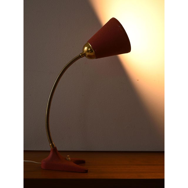 1950s table lamp with red lampshade and flexible brass arm. Thanks to the adjustable arm the light can be directed...