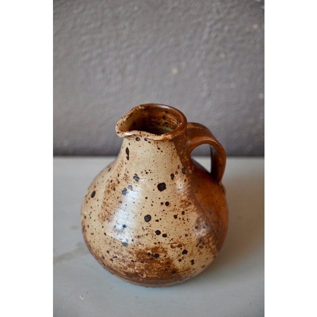This magnificent, bulbous pitcher with its thick, rustic shape is antique. Made of stoneware, it is decorated with...