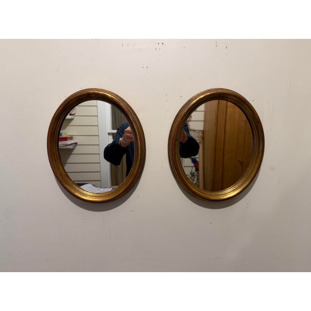 Pair Italian gilt oval mirrors. Each mirror is 11.5" high x 9.5" wide x 1.25" deep. Wire on back for hanging. Good overall...