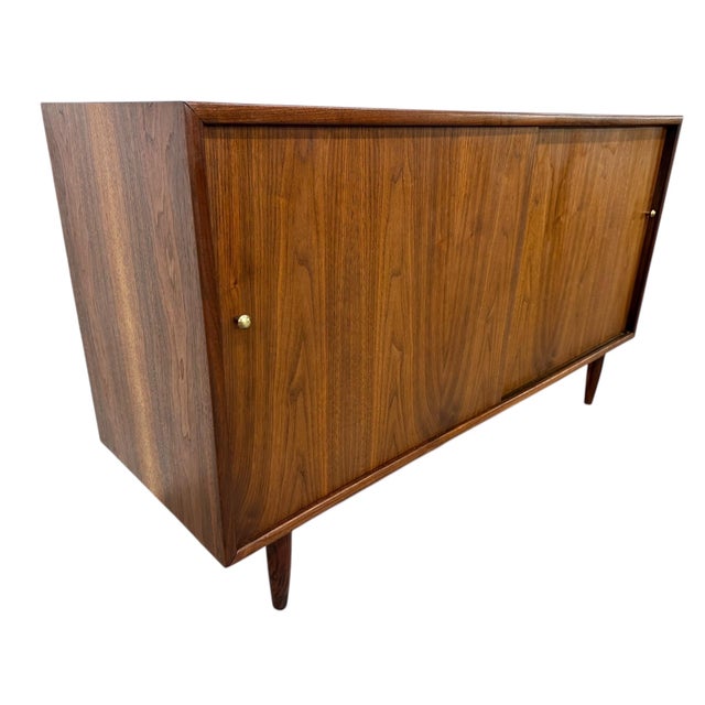 Elevate your space with this stunning 1960s American-made walnut sliding door cabinet, a true Mid-Century Modern classic....