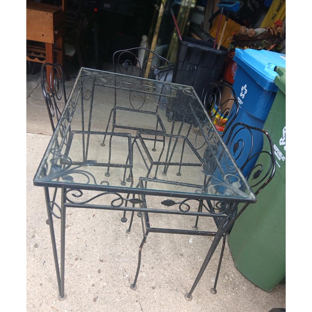 Vintage Outdoor wrought Iron dining set, in black. Unmarked, in the style of Salterini. 4 chairs and one table with glass...