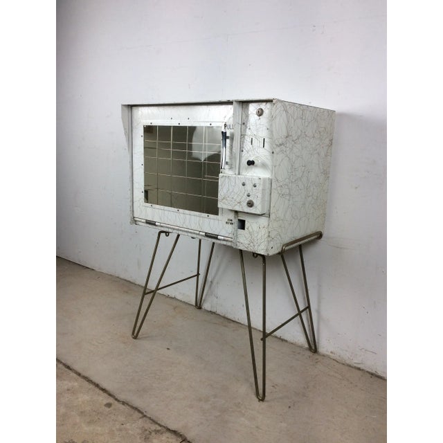 This mid century modern “Sho Rack” freestanding newspaper vending machine features metal construction, white painted...