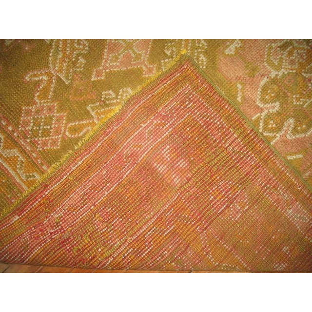 An antique Turkish Oushak, rare size and coloration in predominantly army green with hints of mustard and pinks...