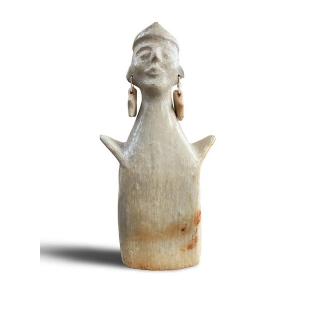A stylized terracotta figure, modeled and partially glazed, depicting an anthropomorphic character with a schematic face...