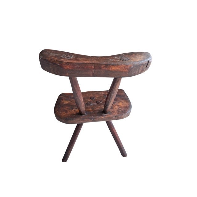 This three-legged wooden stool with a backrest is a striking example of rustic craftsmanship. The design captivates with...