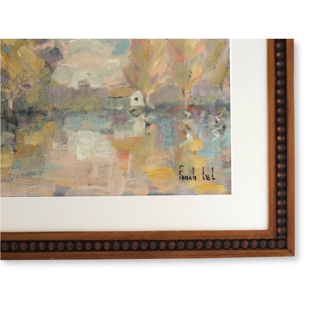 Signed vintage French oil painting depicting a tranquil lakeside landscape with autumnal trees reflected in calm water....