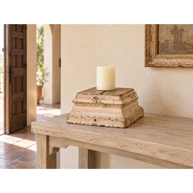 This square column base steps outward in three tiers, wide at the foot and narrowing as it rises, and the paint tells its...