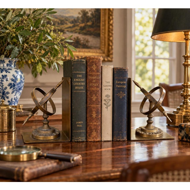 A handsome pair of circa-1980s cast brass bookends modeled as miniature celestial armillary sundials. Intersecting brass...