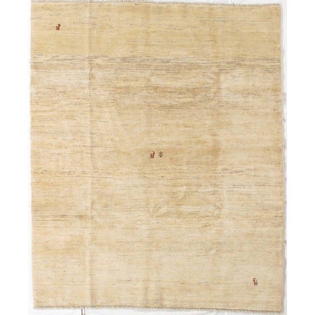 Vintage Hand-knotted Persian Lori Gabbeh rug featuring a soft, minimalist field in warm beige tones with subtle tonal...