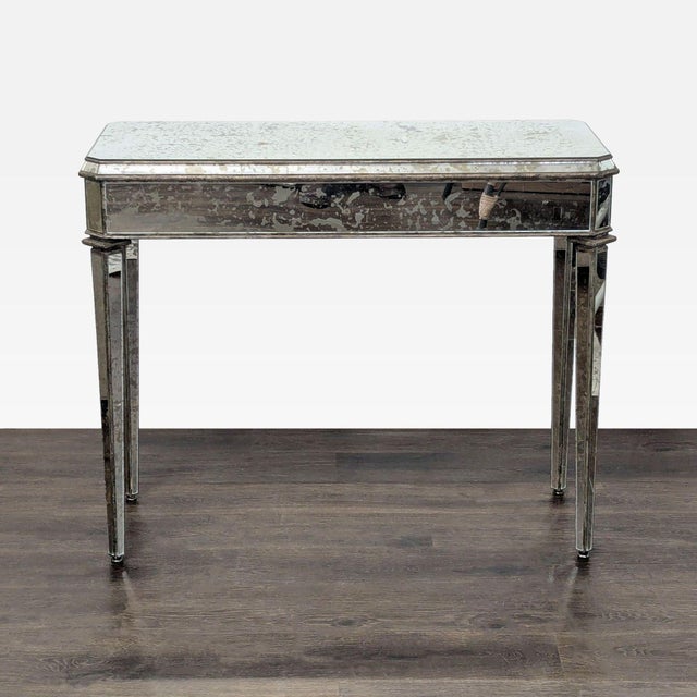 Antiqued mirror one drawer table with tapered pin legs. Brand: Currey & Company. Dimensions (in): 42W x 17D x 34H.