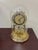 A 9-inch-tall gold quartz anniversary dome clock by Linden with roman numerals and a rotating pendulum mechanism. It's...