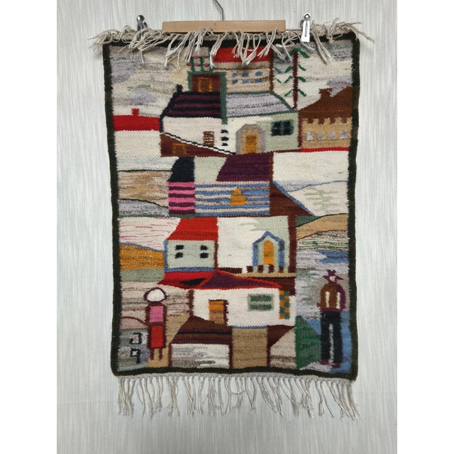 A decorative wall tapestry with a colorful motif of houses and figures, designed by Piotr Grabowski, Poland. Signed GP....