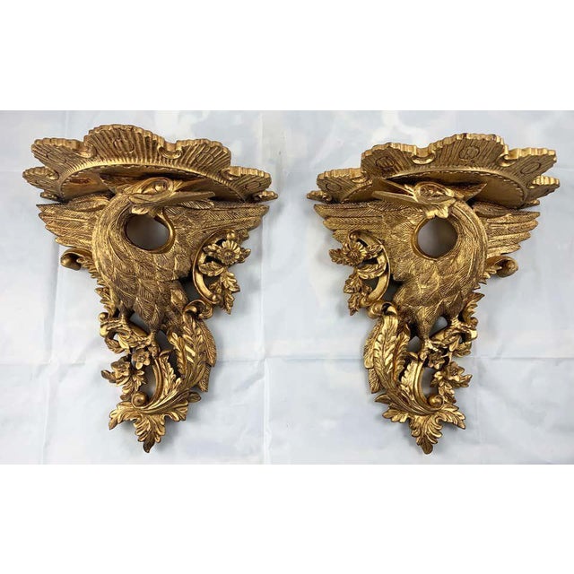 An ornate pair of carved giltwood wall brackets. Made in france in the 19th century. Each one features a hand carved pair...